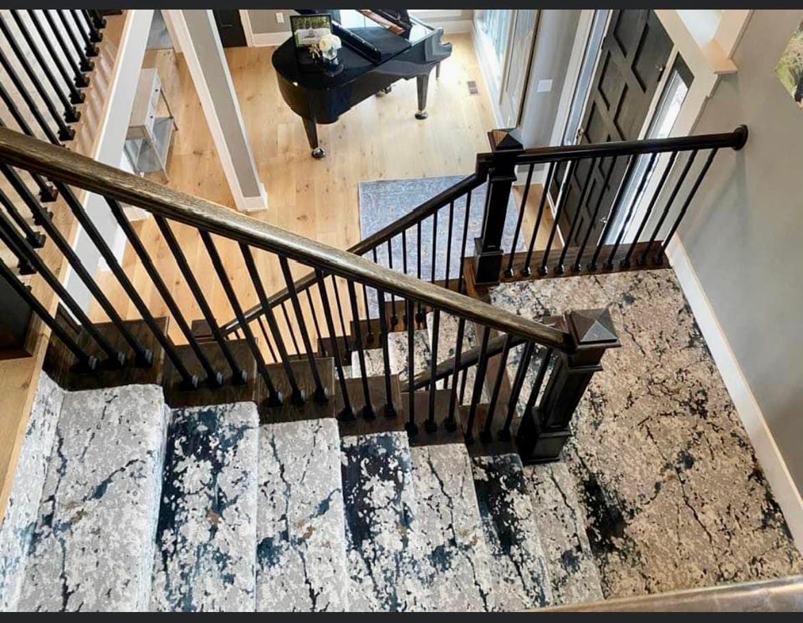 Staircase with a patterned runner overlooking a bright Kansas City great room