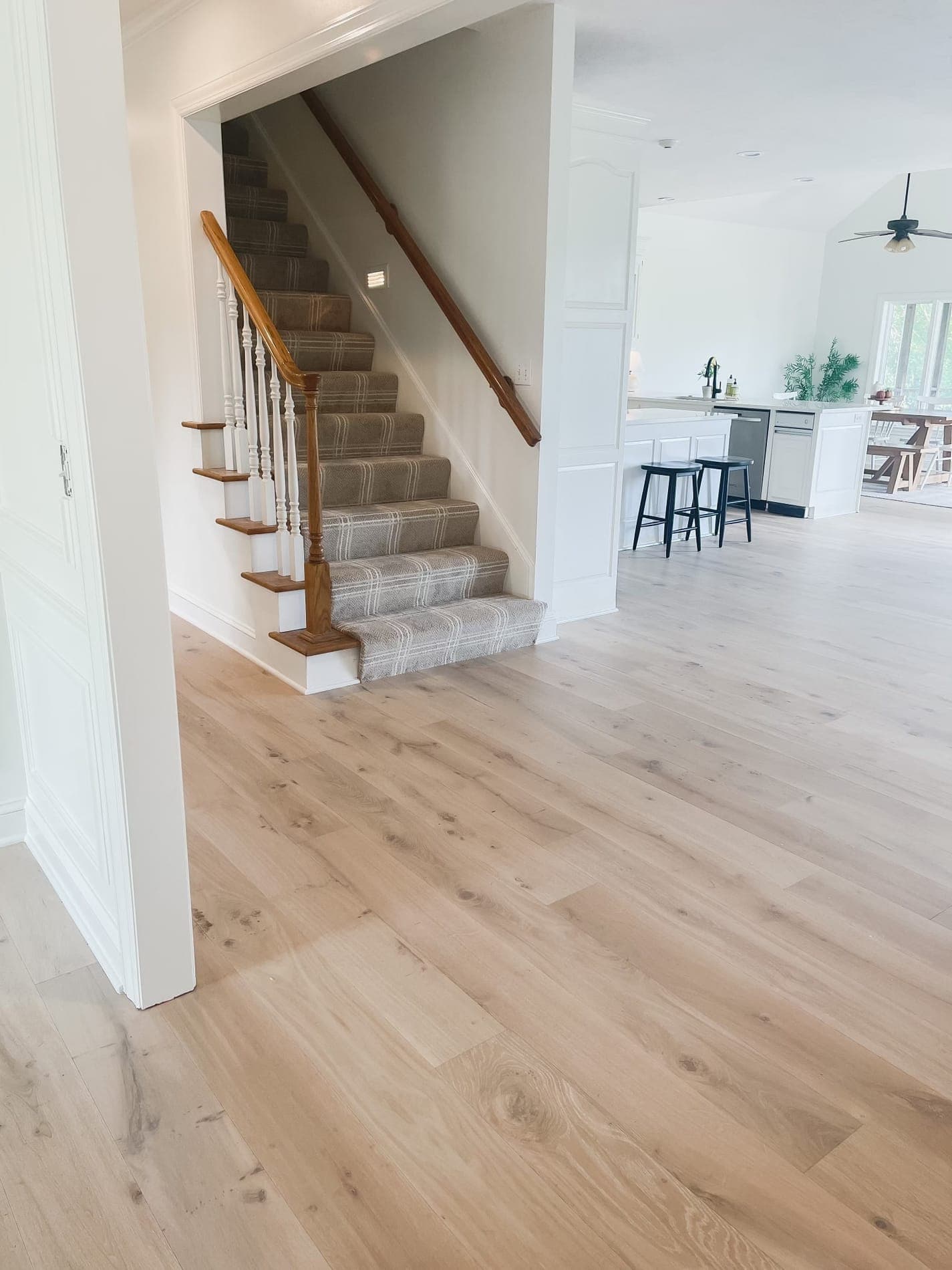 Sunlit open living space with hardwood flowing to a stair runner